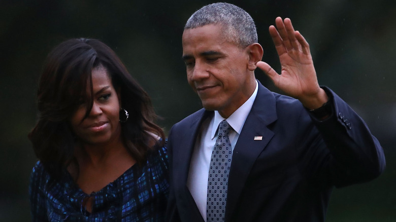 Barack and Michelle Obama walking together on the lawn.