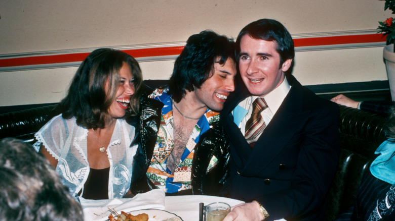 Freddie Mercury at a party, seated and laughing