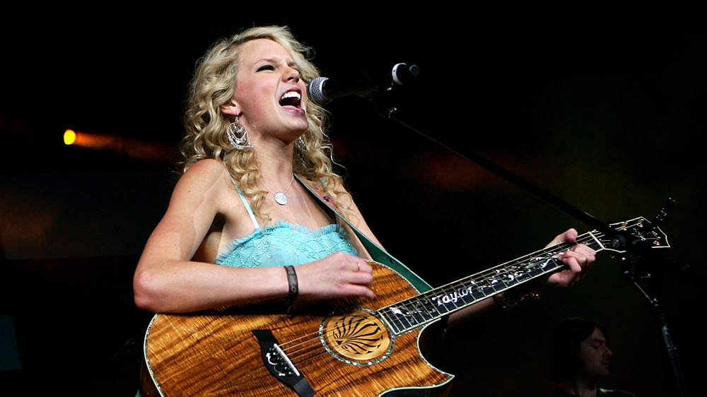 Taylor Swift playing guitar on stage