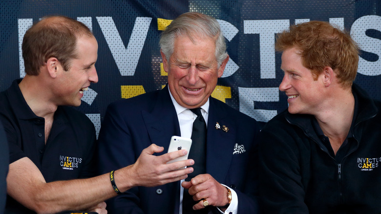 King Charles III laughing with Princes William and Harry