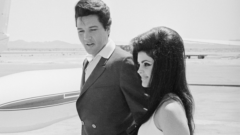 Elvis Presley and Priscilla Presley walking near airplane