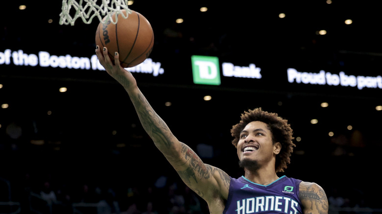 Kelly Oubre Jr. holding a basketball near the net