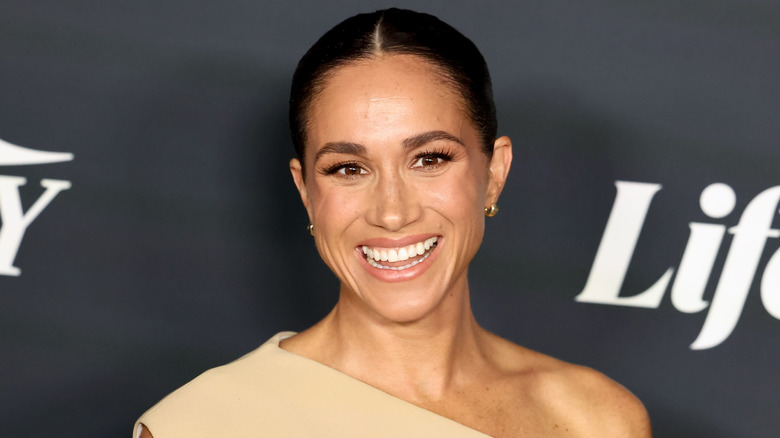 Meghan Markle, Duchess of Sussex, wearing beige one-shoulder dress