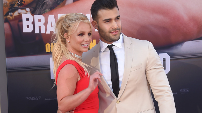 Britney Spears waving beside Sam Asghari