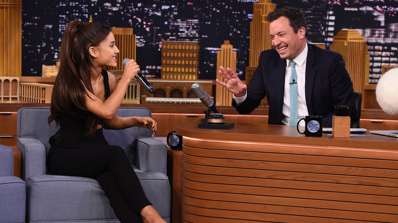 Ariana Grande holding a mic next to Jimmy Fallon during a "The Tonight Show" guesting