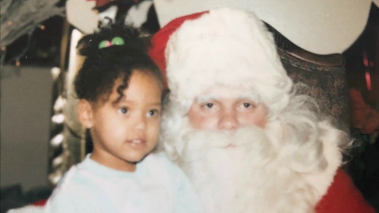 Ayesha Curry as a child, sitting on Santa's lap