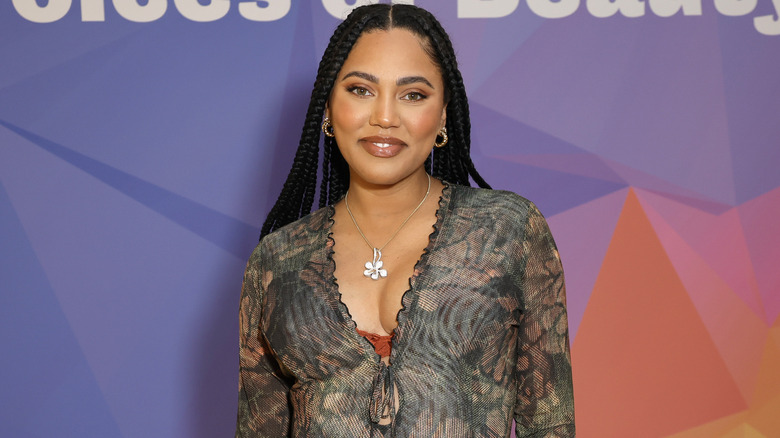 Ayesha Curry smiling on a red carpet prior to having her fourth baby