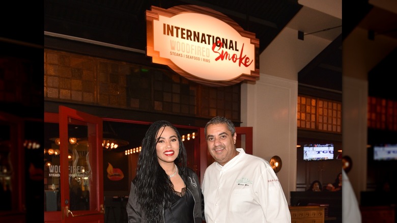 Ayesha Curry and chef Michael Mina posing at their restaurant, International Smoke