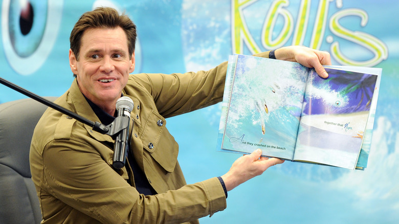 Jim Carrey holding his book up