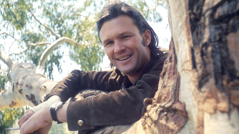 Kris Kristofferson posing against a tree branch in 1968