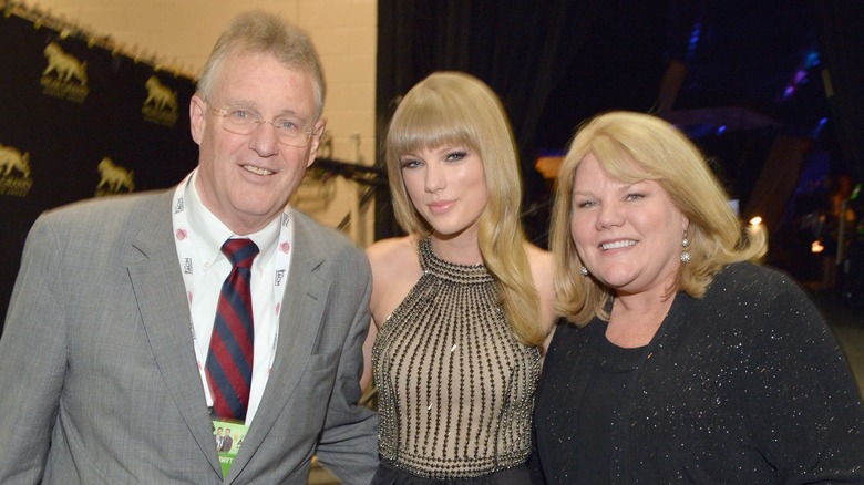 Taylor Swift posing with her parents at an event