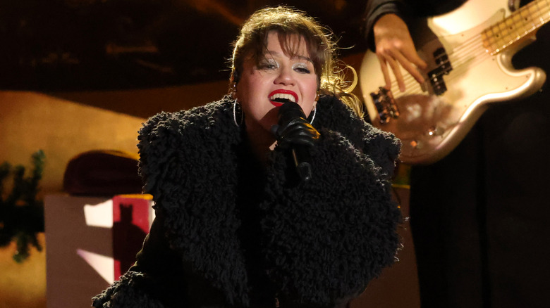 Kelly Clarkson singing in large black coat