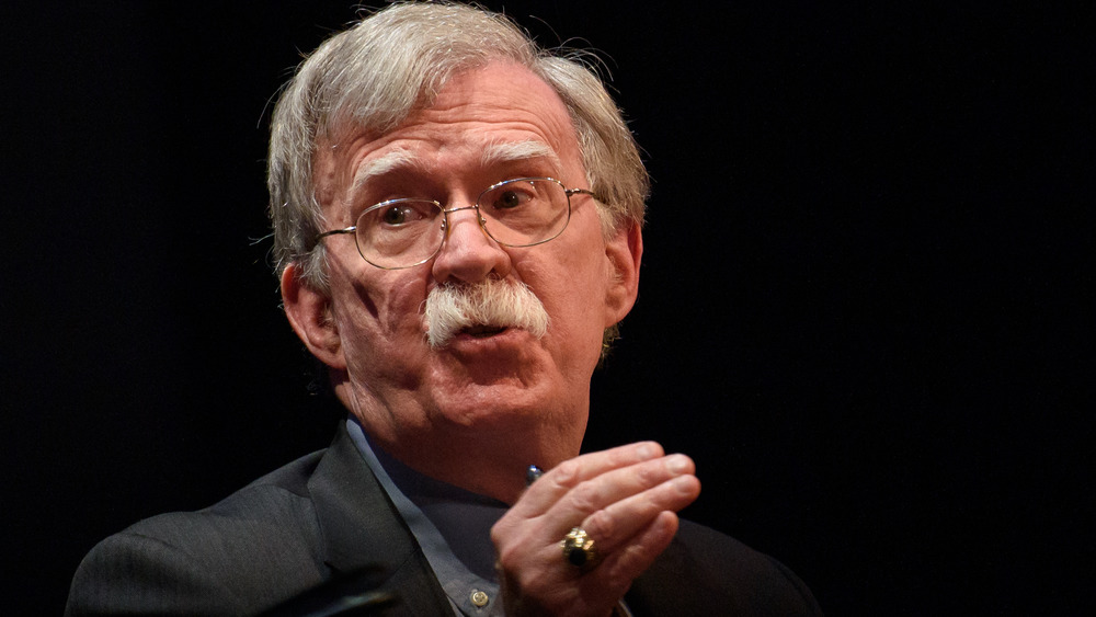 John Bolton speaking, hand raised