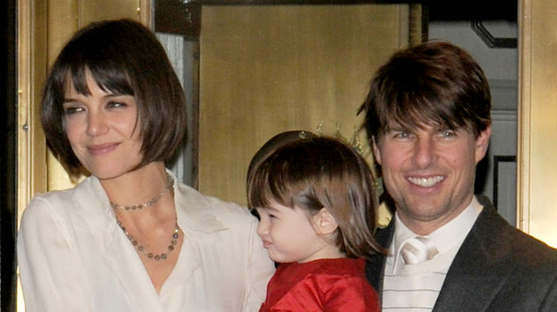 Katie Holmes holding Suri Cruise Tom Cruise grinning