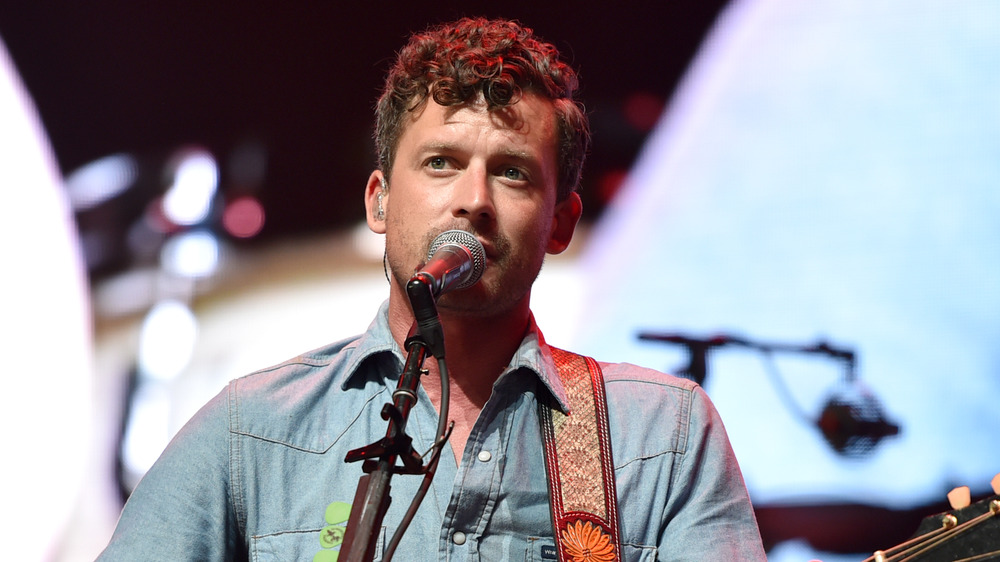 Evan Felker, singing into a microphone, jean shirt, on stage in 2018, with guitar