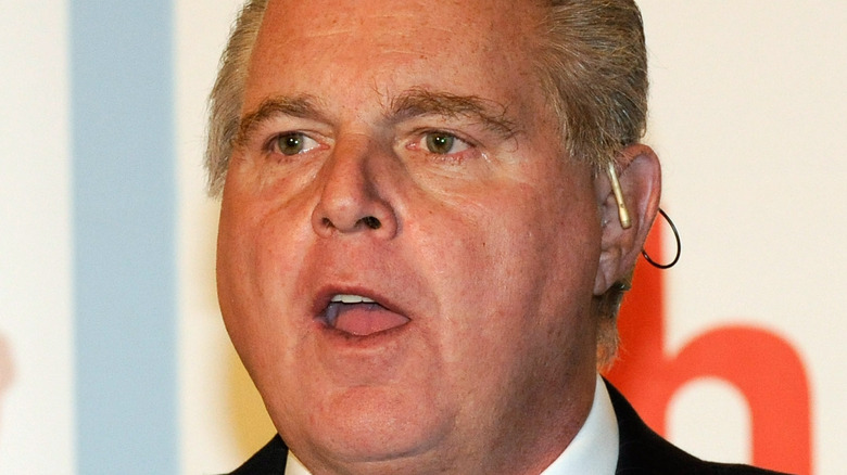 Rush Limbaugh talking on stage, wearing earpiece