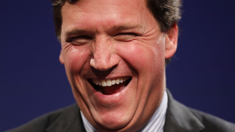 Tucker Carlson laughing grey suit stripe shirt