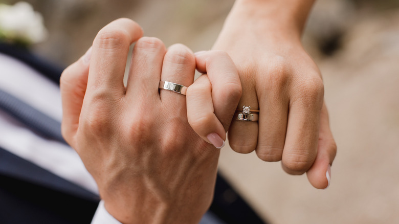 Married couple's hands, with pinkies intertwined 