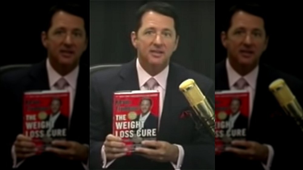 Kevin Trudeau holding a copy of his book The Weight Loss Cure 