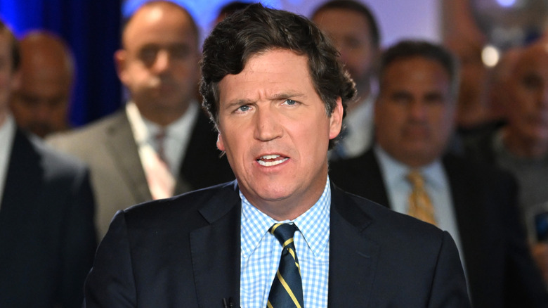 Tucker Carlson anchoring a news broadcast