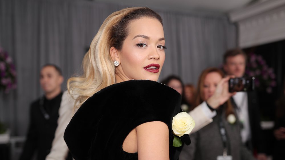 Rita Ora in a black dress, looking over her shoulder