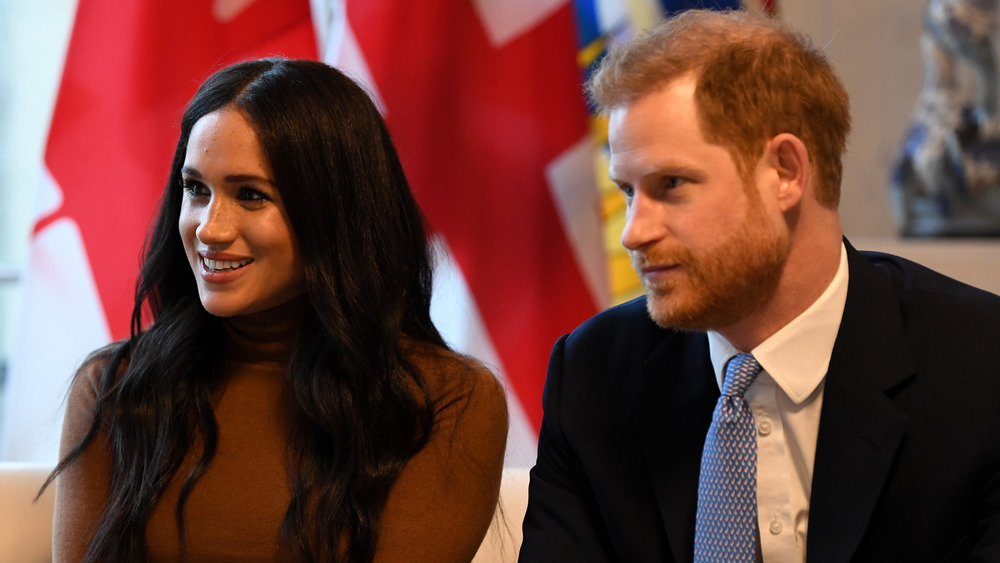 Meghan Markle smiling while seated next to Prince Harry at Canada House 