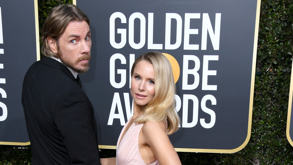 Dax Shepard and Kristen Bell posing while looking over their shoulders