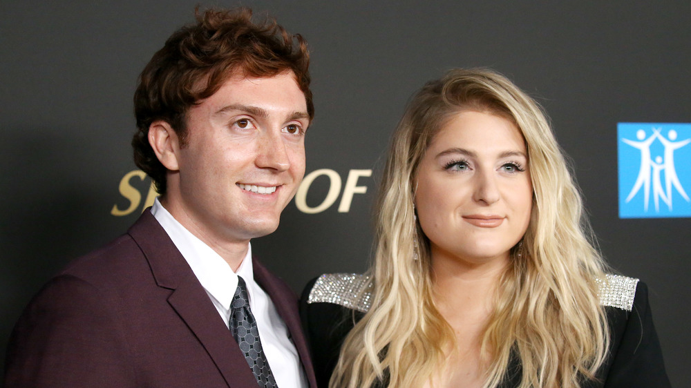 Daryl Sabara and Megan Trainor smiling while looking off to the side