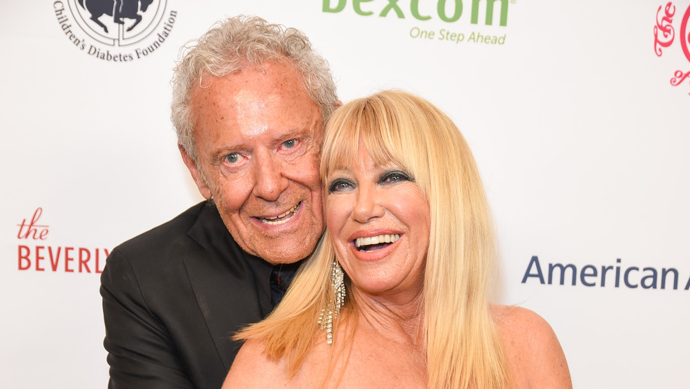 Alan Hamel hugging Suzanne Somers from behind, both laughing