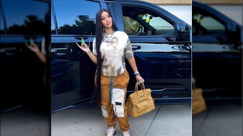 Cardi B posing in front of a car