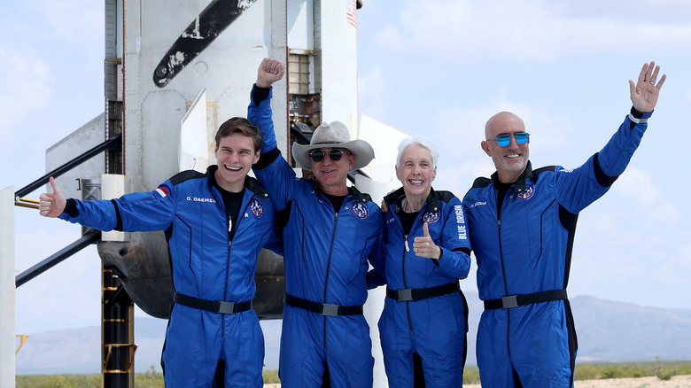 Jeff Bezos and team waving in front of rocket