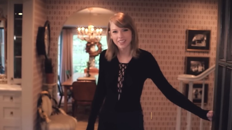 Taylor Swift smiling and opening door