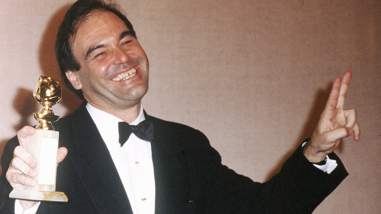 Oliver Stone smiling and holding Golden Globe