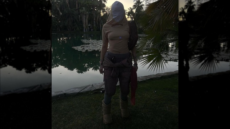 Noah Cyrus posing outdoors in a Luke's Thunder outfit with a balaclava