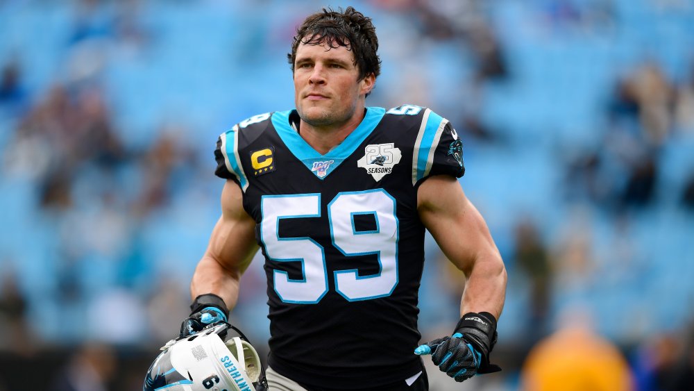 Luke Kuechly running onto the field, holding his helmet