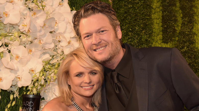 Miranda Lambert and Blake Shelton posing in front of flowers