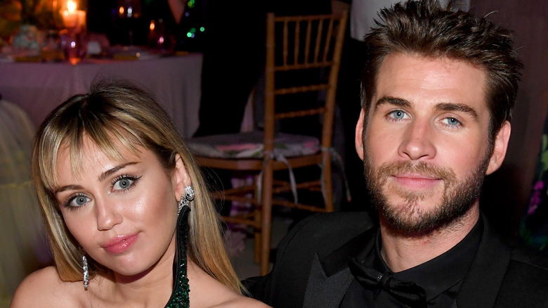 Miley Cyrus and Liam Hemsworth seated at a table