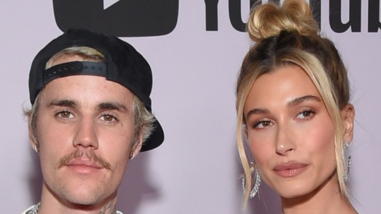 A mustachioed Justin Bieber and Hailey Bieber posing