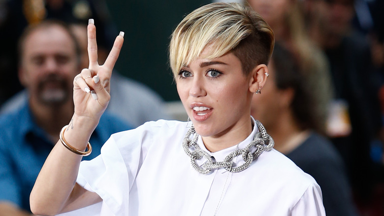 Miley Cyrus throwing up a peace sign