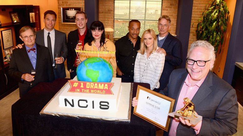 The cast of NCIS posing together with a cake