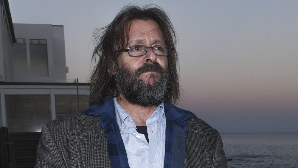 A bearded Judd Nelson with long, messy hair 