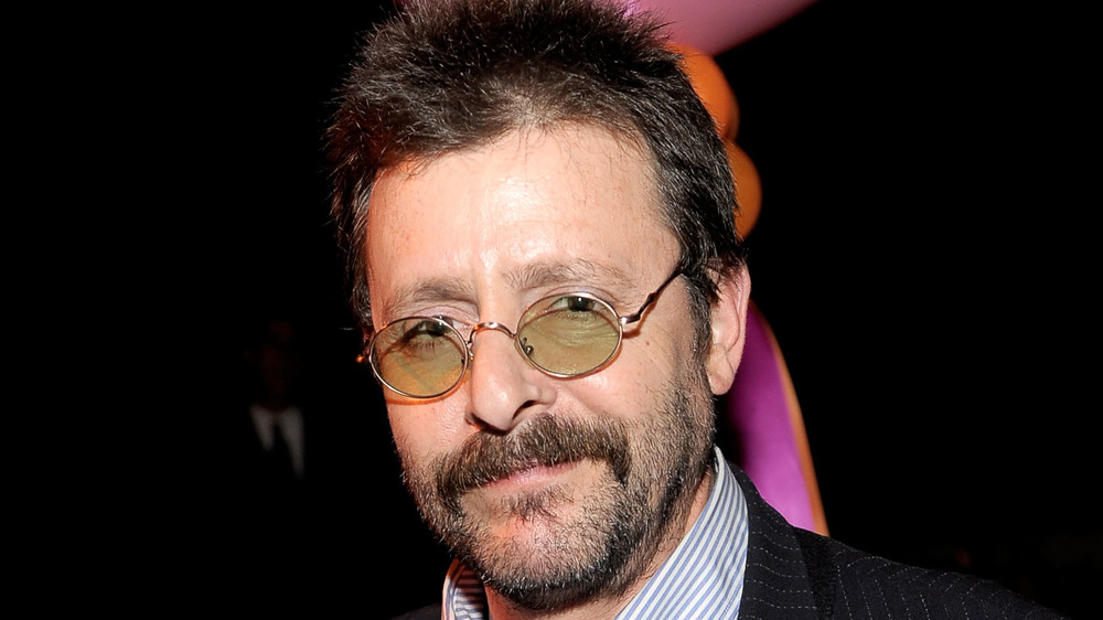 Judd Nelson smiling, wearing tinted glasses