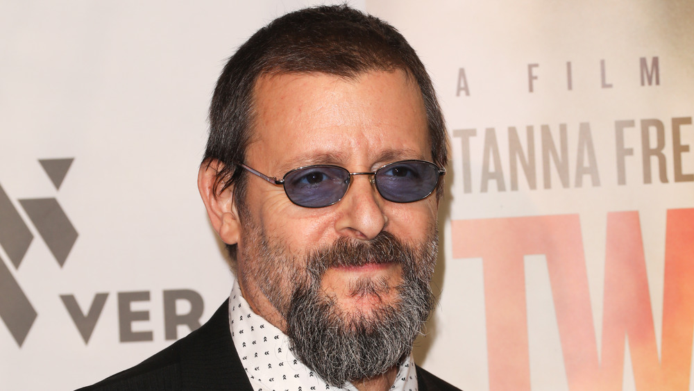 Judd Nelson smirking, wearing glasses and a beard