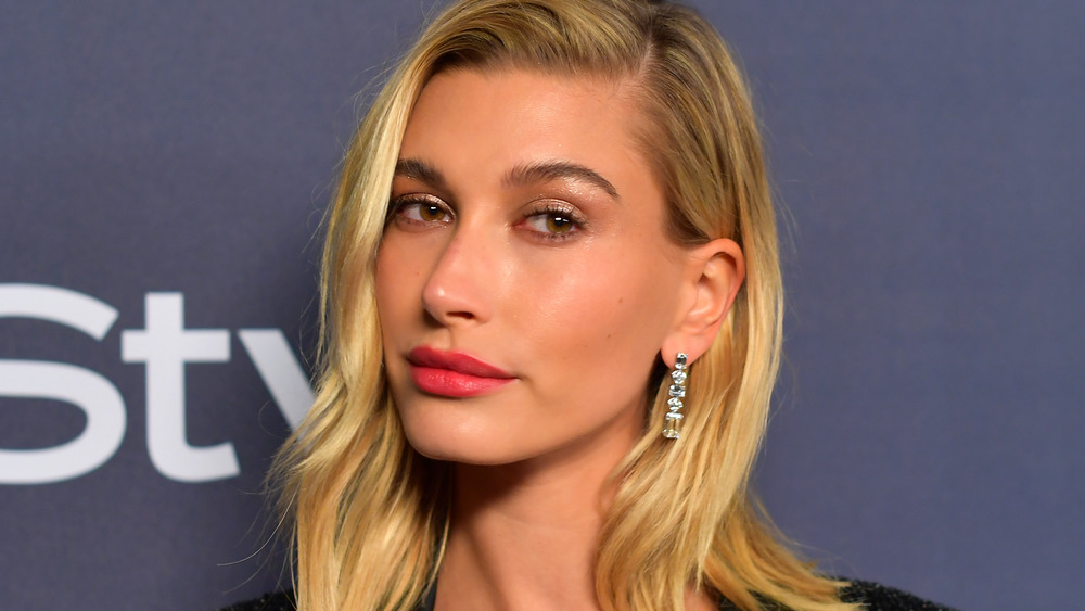 Hailey Baldwin smirking with red lipstick