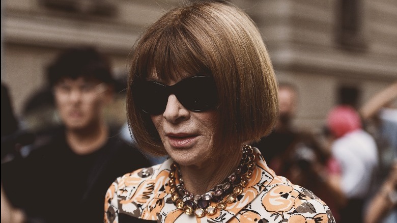 Anna Wintour wearing orange dress and sunglasses 