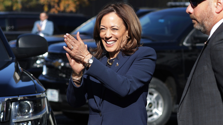 Kamala Harris smiles and claps while wearing her trademark pantsuit.