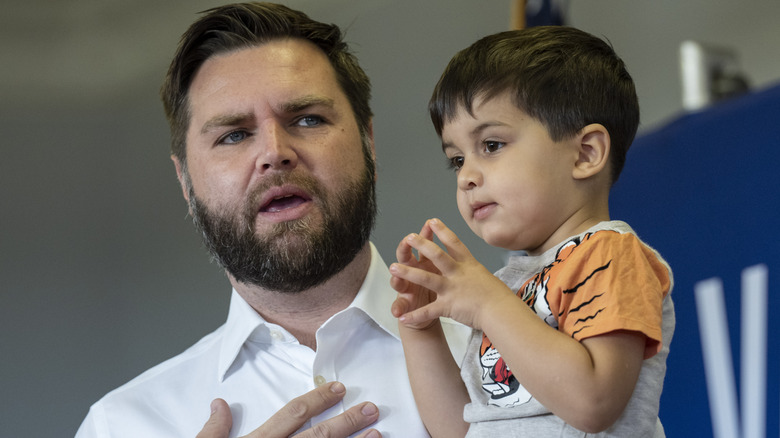 JD Vance holds his son while talking at a get-out-the-vote event.