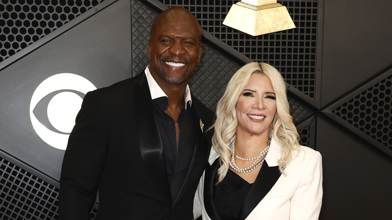 Terry Crews and Rebecca King-Crews smiling with teeth and wearing black-and-white outfits