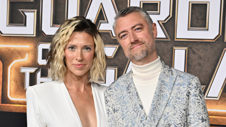 Natasha Halevi and Sean Gunn stand at a red carpet event