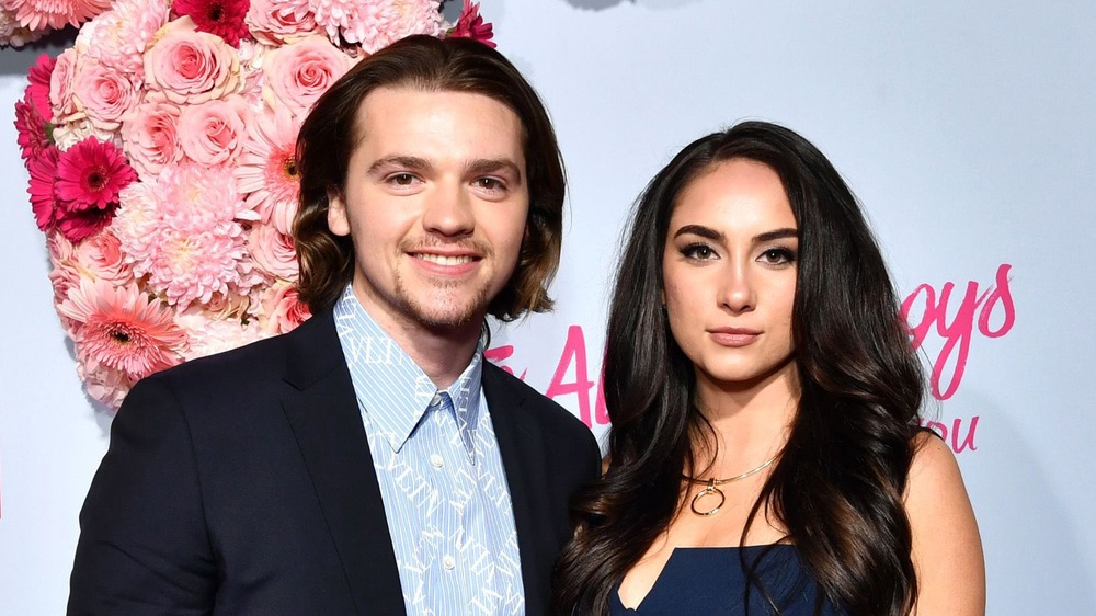 Joel Courtney and Mia Scholink smiling on a red carpet 